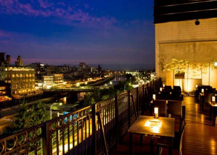 The outdoor terrace of Tendan Gion Honten at night, looking out over the Gion district of Kyoto.